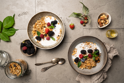Zwei Schüsseln Joghurt mit Müsli auf dem Tisch.